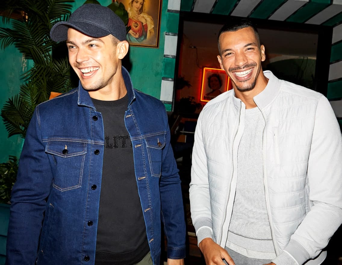 Two men smiling outside a bar