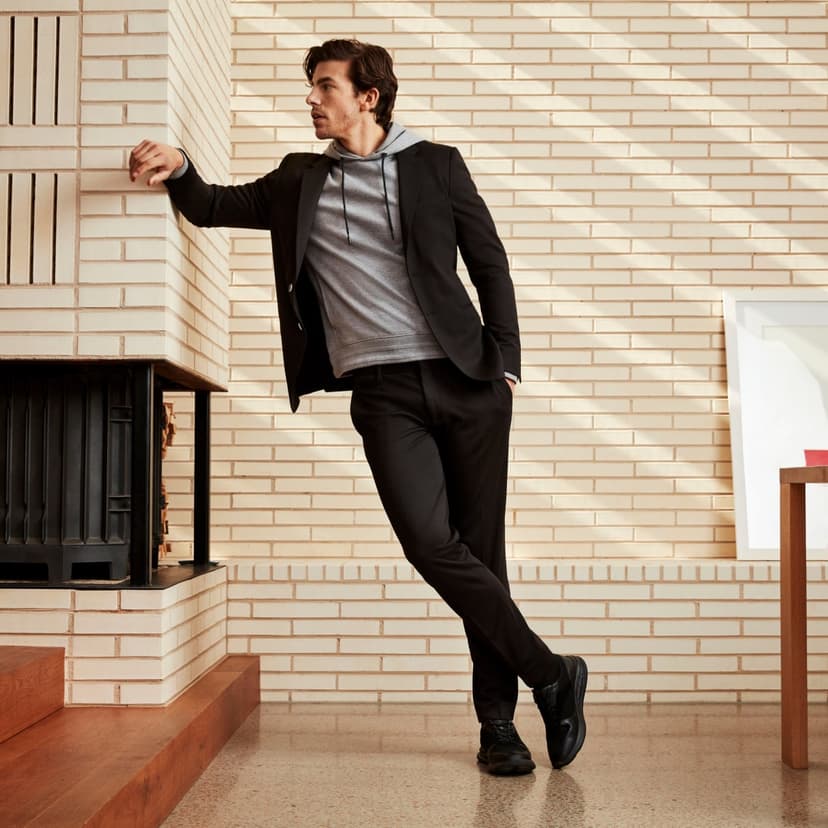 Man dressed in black leaning on brick wall