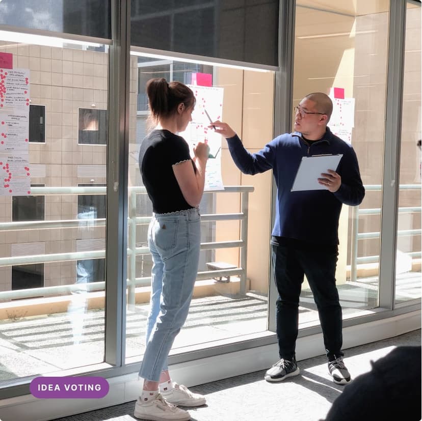 Two people stand and pointing at a wireframe sketch